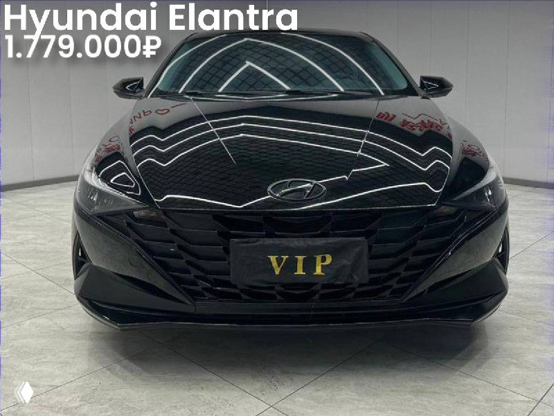 Фотография чёрной Hyundai Elantra спереди в боксе/шоуруме, крупный план капота и бампера, видна декоративная табличка "VIP" на фото.