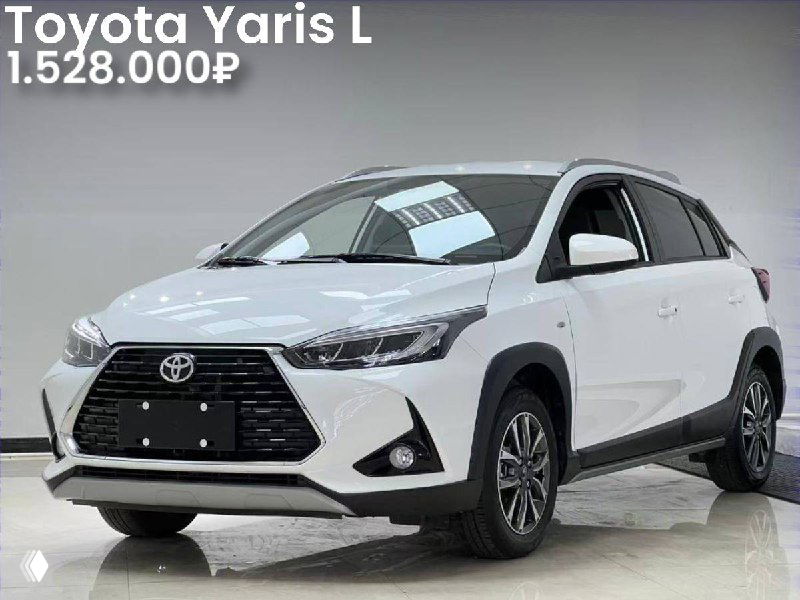 Фотография Toyota Yaris L белого цвета в выставочном зале, боковой и фронтальный ракурс, видны бампер, фары и диски, цена указана отдельно в посте.