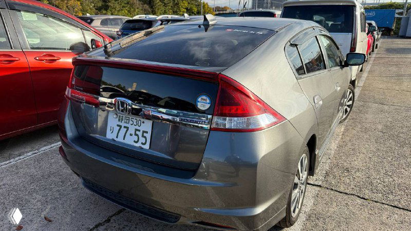 Задняя часть серой Honda Insight Hybrid 2011: багажник и задние фонари, вид на заднюю дверь и японский номер на парковке в Японии.