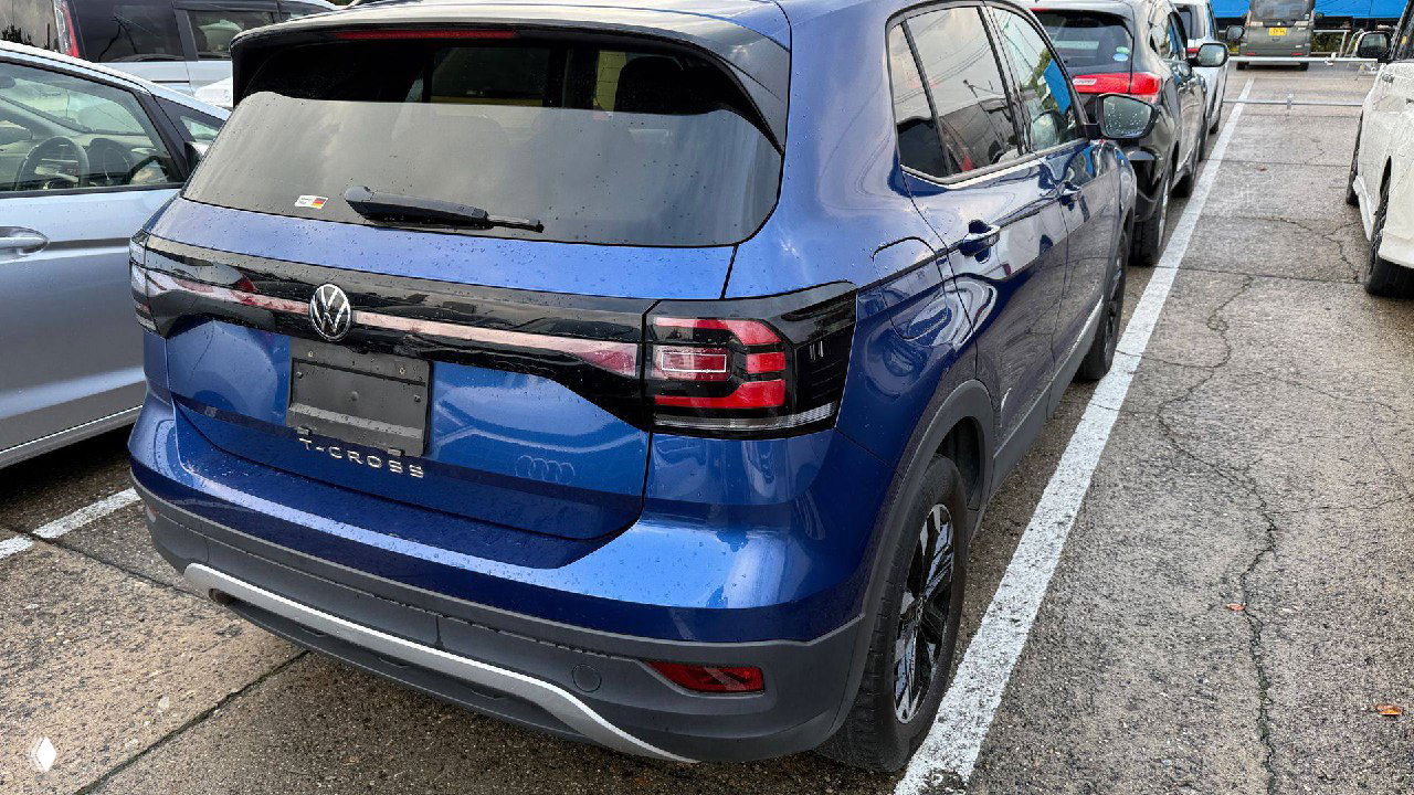 Задняя часть синего Volkswagen T‑Cross 2022 на парковке, видна крышка багажника, задние фары и штатный номерный фон для экспорта