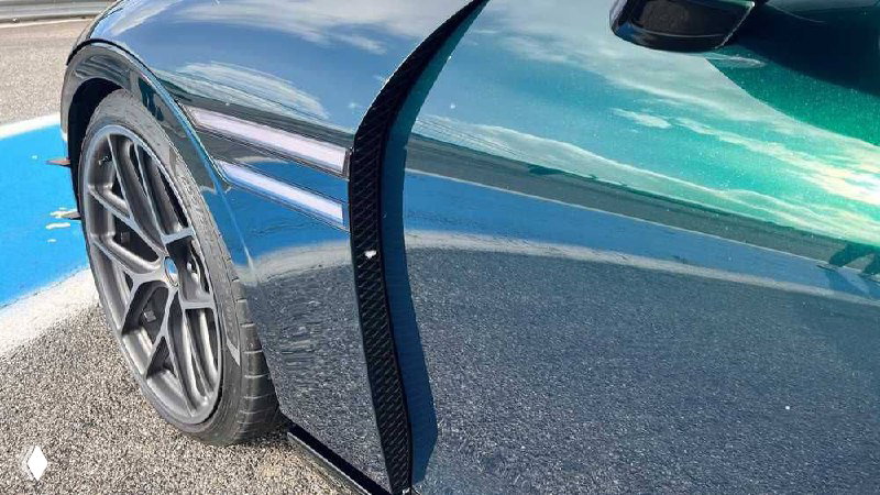 Деталь: заднее колесо и крыло Genesis G90 Wingback, крупный план на аэродинамический элемент и тёмный спойлер на корпусе универсала.