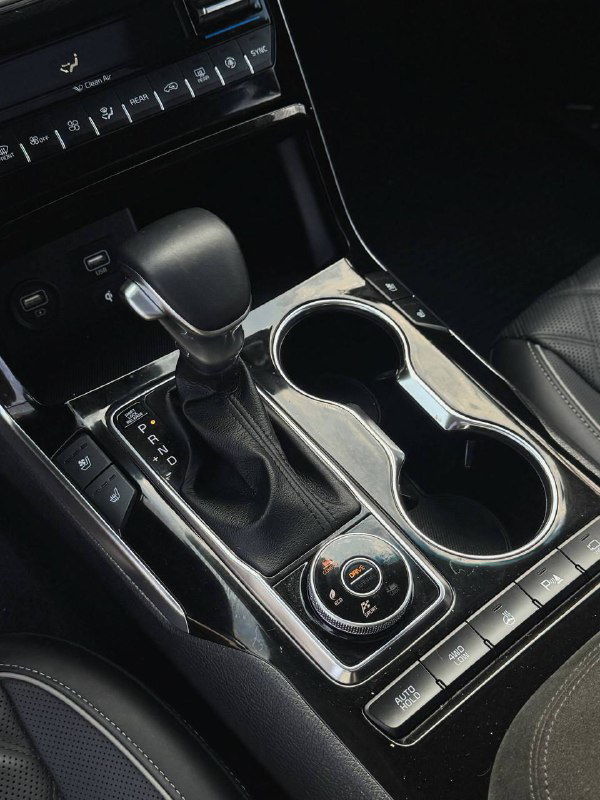 Ближний план селектора передач и подстаканников в центральной консоли KIA Mohave, хромированные элементы и глянцевая отделка.