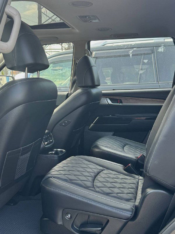 Второй ряд сидений KIA Mohave, салон с просторными креслами и проходом между сиденьями; вид на задний отсек.