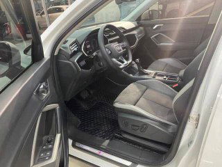 Водительское место Audi Q3: открытая дверь, сиденье, поручни и порог с подсветкой, видна часть салона и приборов.