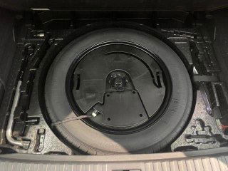 Ниша с запасным колесом под полом багажника Audi Q3, видна канистра для инструмента и аккуратно уложенное запасное колесо.