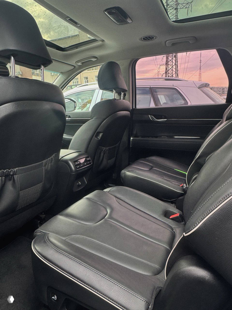 Вид задних сидений Hyundai Palisade: три посадочных места, подлокотник и вентиляционные решётки с панелью управления климатом для задних пассажиров.