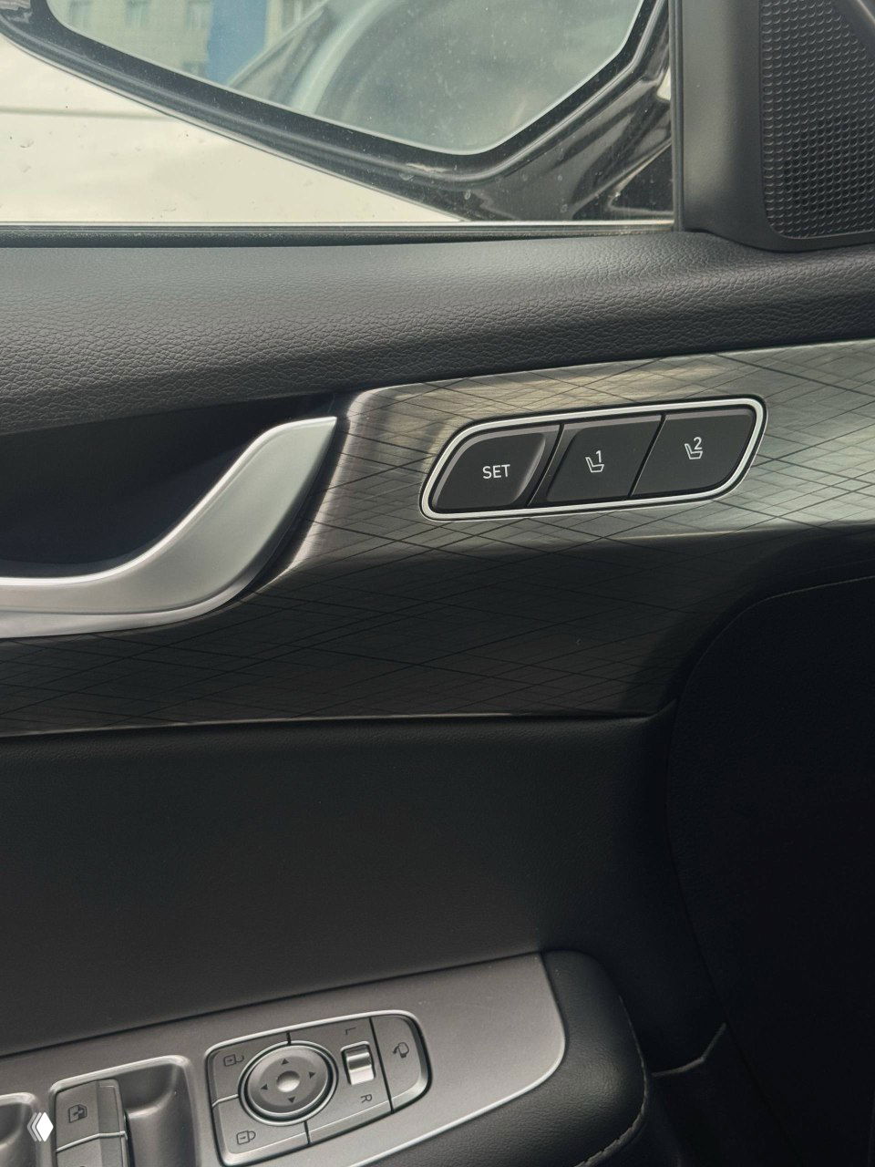 Крупный план дверной ручки и клавиш памяти положения сиденья в Hyundai Palisade, видна декоративная отделка и элементы управления стеклоподъёмниками.