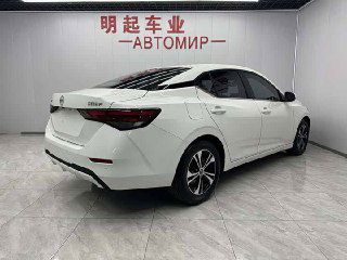 Белый Nissan Sylphy 2022, вид сзади справа в салоне-показе, видны задние фонари, багажник и профиль кузова седана.