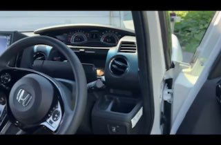 Рулевое колесо и передняя правая дверь Honda N BOX CUSTOM: элементы управления, обивка и состояние водительской зоны при осмотре на парковке.