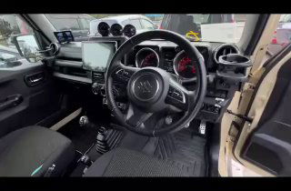 Салон Suzuki Jimny Sierra 2021: рулевое колесо, мультимедийная панель ALPINE с монитором камеры и общий вид водительского места.