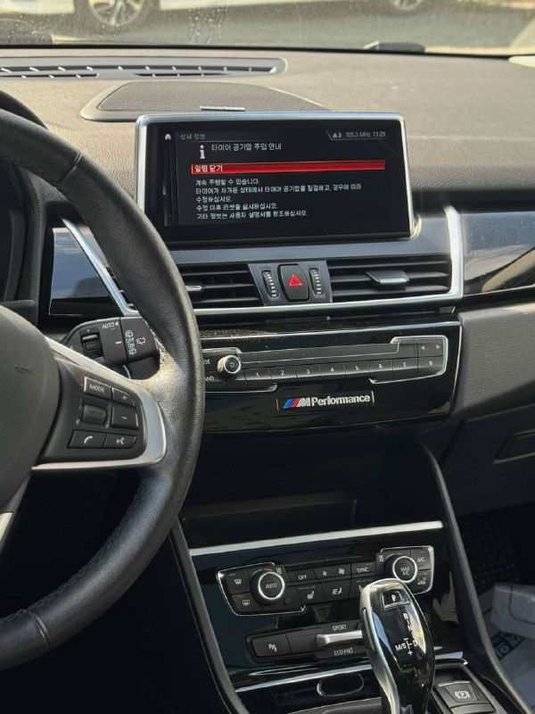 Центральная консоль BMW 2-Series Active Tourer с экраном мультимедиа, кнопками управления и декоративными элементами в интерьере.