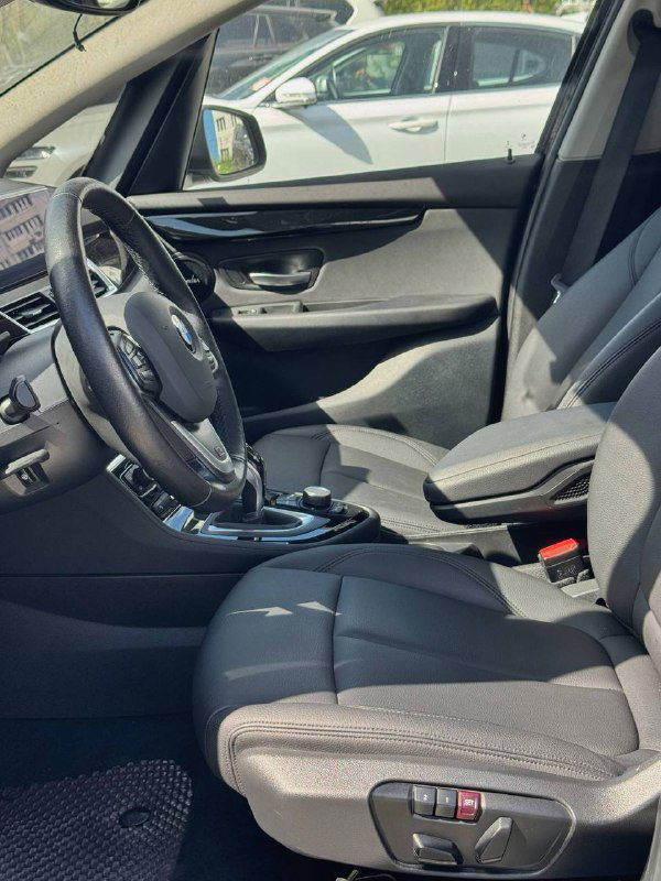 Боковой вид салона BMW: передние сиденья, дверная панель и центральная консоль, демонстрирующие пространство и материал обивки.