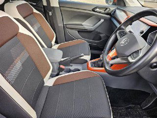 Передние сиденья Volkswagen T‑Cross 2021 с тканевой комбинированной обивкой коричнево‑серого тона и контрастными швами, вид пассажирской зоны и кресел.