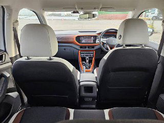 Вид сзади на передние кресла и торпедо Volkswagen T‑Cross 2021: демонстрация внутреннего пространства, конструкции передних сидений и центрального тоннеля.