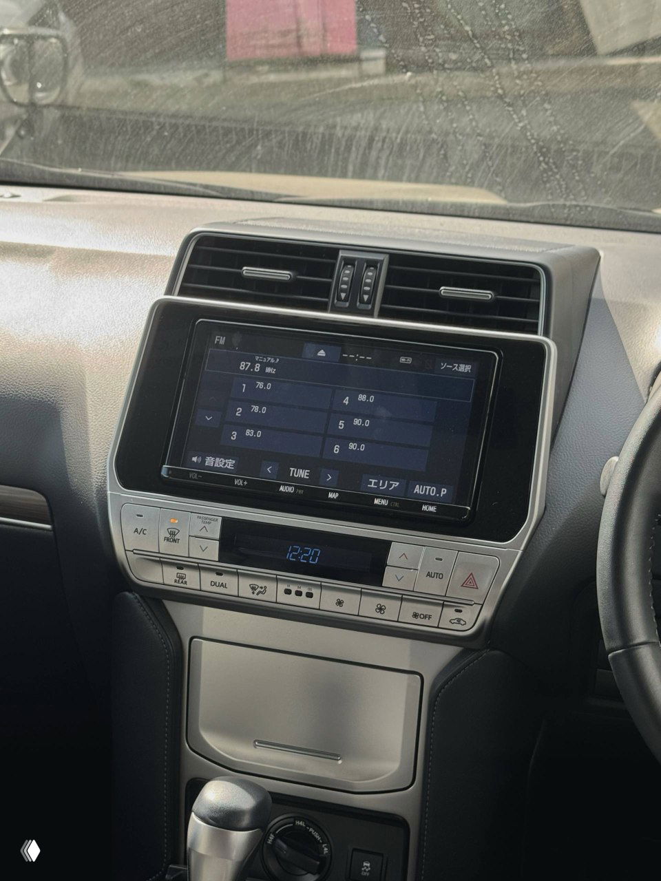 Центральная консоль Toyota Prado: мультимедийный экран, элементы управления климатом и панель с расположением кнопок, общий вид из кабины водителя.