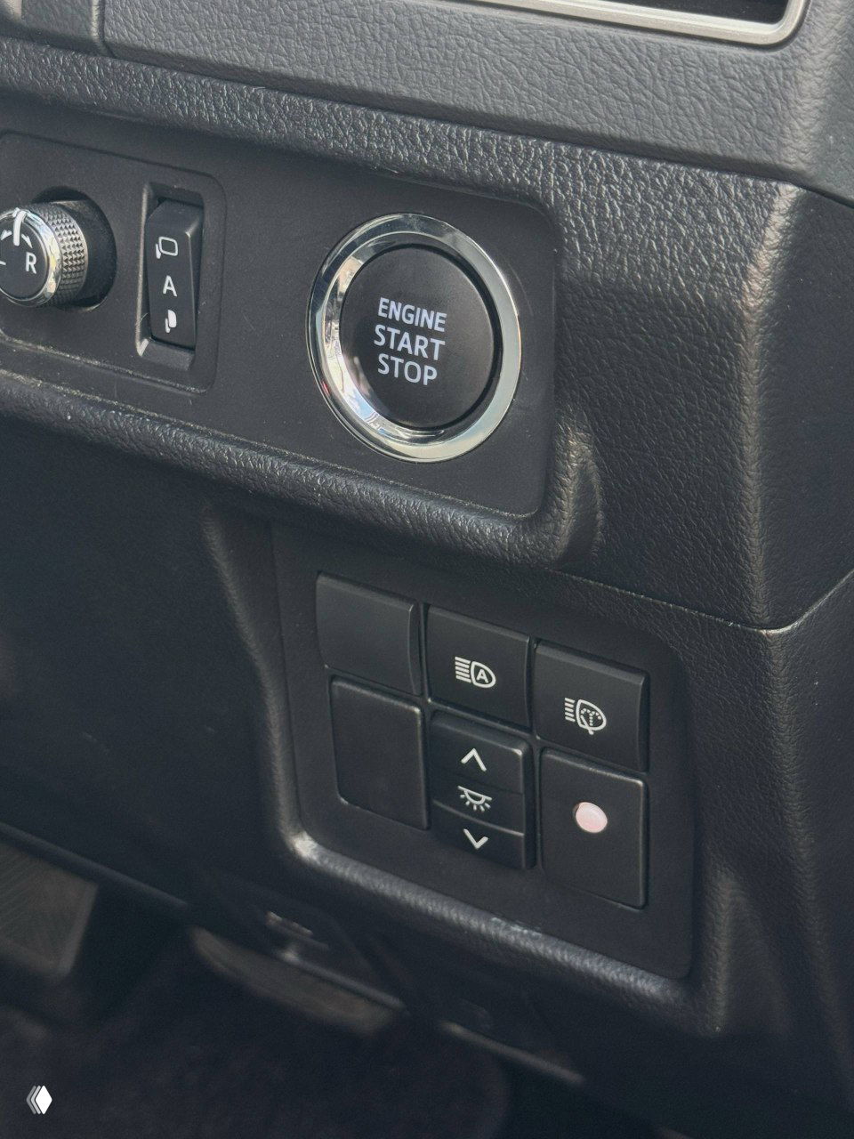Крупный план кнопки ENGINE START STOP и блока переключателей световых режимов на панели слева от руля — вид элементов управления и отделки.