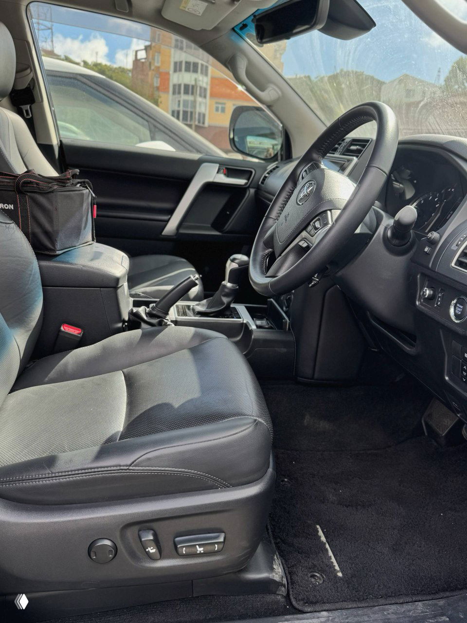 Передние сиденья и центральный тоннель Toyota Prado, кожаная обивка, положение сидений и обзор водительского места с панорамой салона.