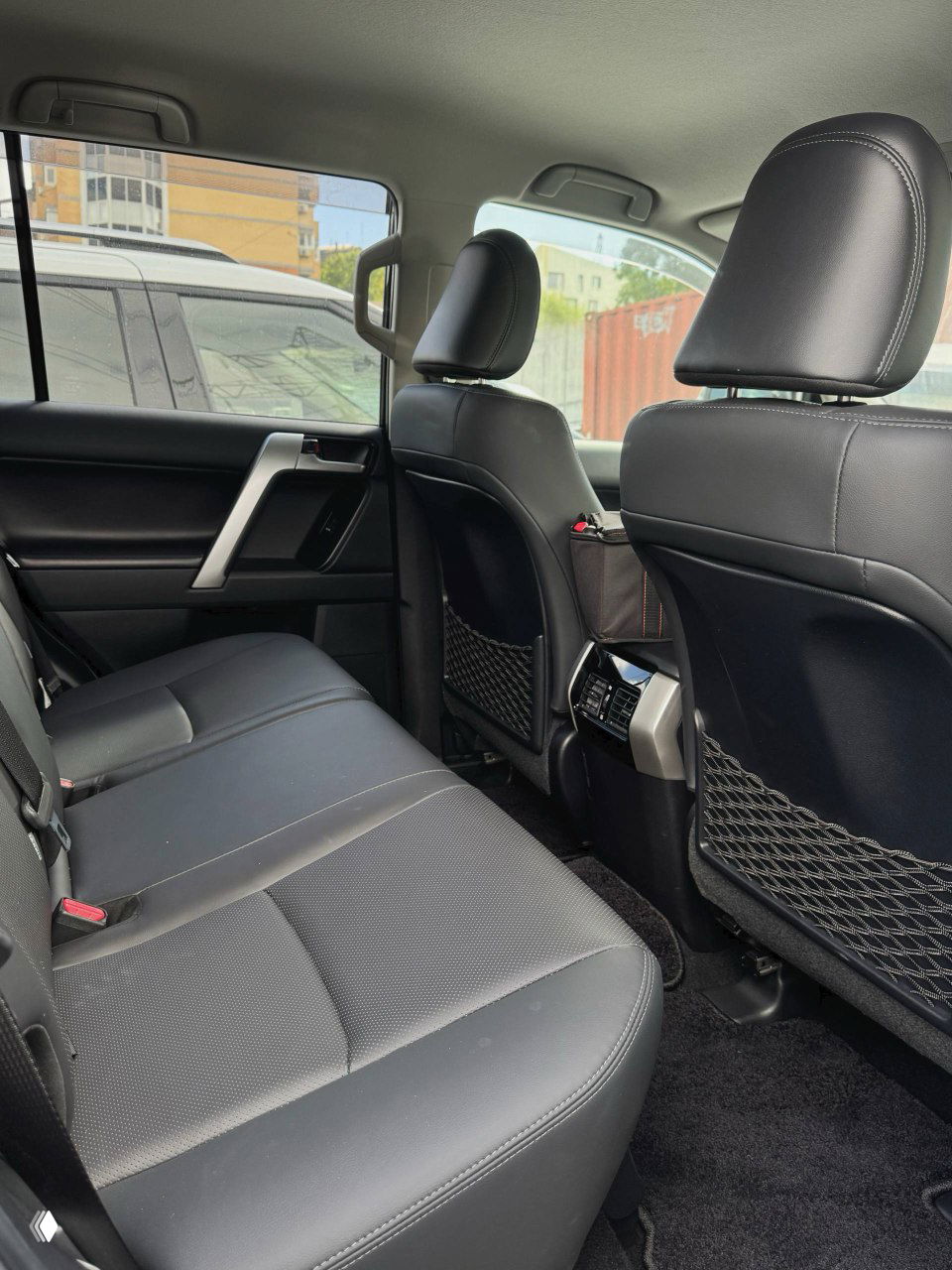 Задний ряд сидений Toyota Prado: обзор места для пассажиров, обивка сидений, подголовники и пространство для ног, вид с левой стороны салона.