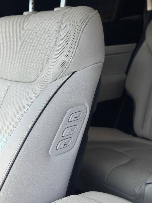Крупный план боковой панели сиденья с кнопками регулировки положения и поясничной поддержки в светлой кожаной обивке рестайлингового Palisade.