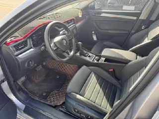 Кабина водителя Skoda Superb: руль, приборная панель и селектор передач, сиденье водителя и элементы управления — вид со стороны водительской двери.