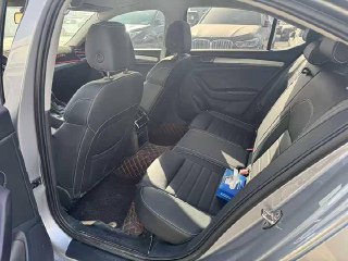 Задний ряд Skoda Superb: задние сиденья и пространство для ног, предметы на полу; общий вид отделки салона и задней части автомобиля.