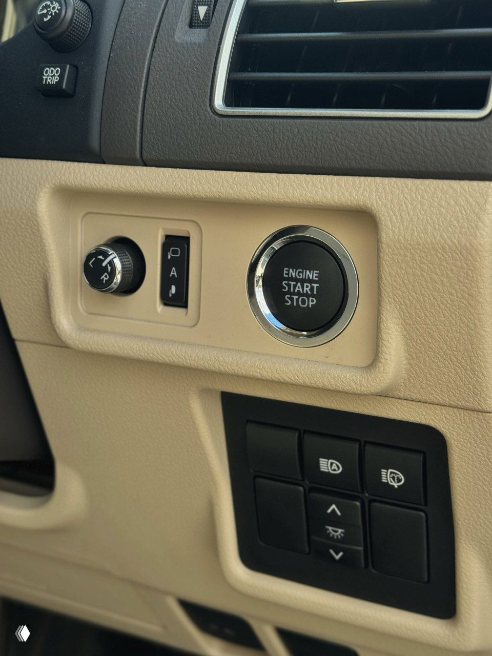 Блок кнопок у панели приборов и кнопка ENGINE START STOP в салоне Prado 2021; крупный план элементов управления и отделки бежевого интерьера