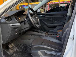 Передние сиденья Skoda Octavia 2022 с кожаной отделкой, вид на руль, селектор робота и центральный подлокотник.