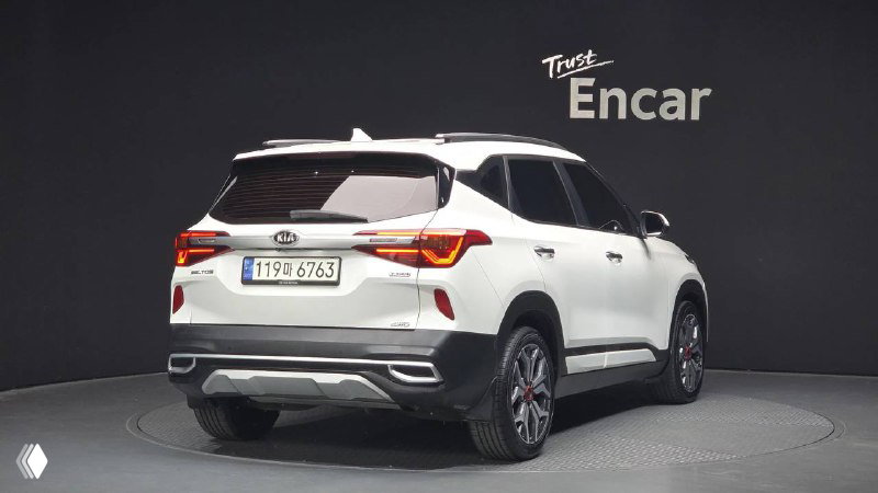 Белый KIA Seltos Signature 2021, вид сзади на автосалоне: фонари, задний бампер и общий силуэт автомобиля