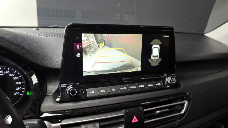 Мультимедийный экран KIA Seltos показывает изображение камеры заднего вида и разметку парковки, интерфейс на экране