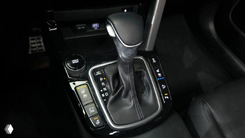 Рычаг переключения передач и область селектора в KIA Seltos, видны кнопки управления и декоративная отделка вокруг КПП