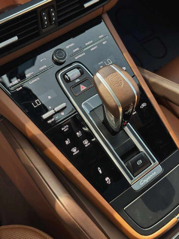 Селектор коробки передач и центральный тоннель Porsche Cayenne с кожаной отделкой, кнопки управления климатом и декоративные вставки на фото.