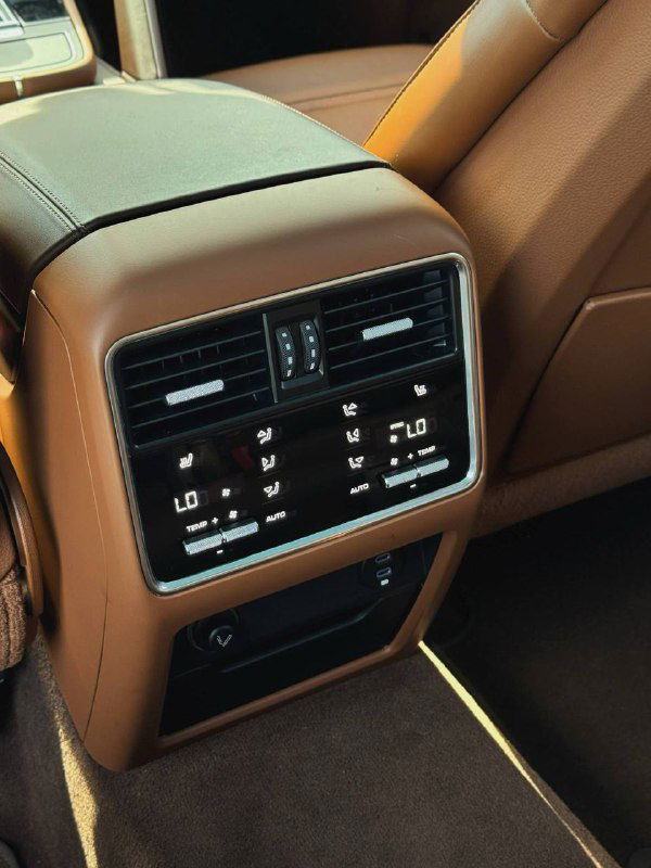 Панель заднего климата и элементы управления на спинке центрального подлокотника, видны цифровые индикаторы и воздуховоды для пассажиров сзади.