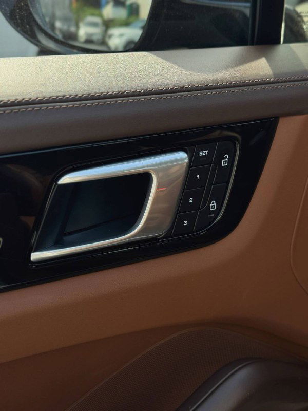 Дверная ручка и панель с элементами управления стеклоподъёмниками и памятью сиденья на передней двери Porsche, видна отделка и кнопки.