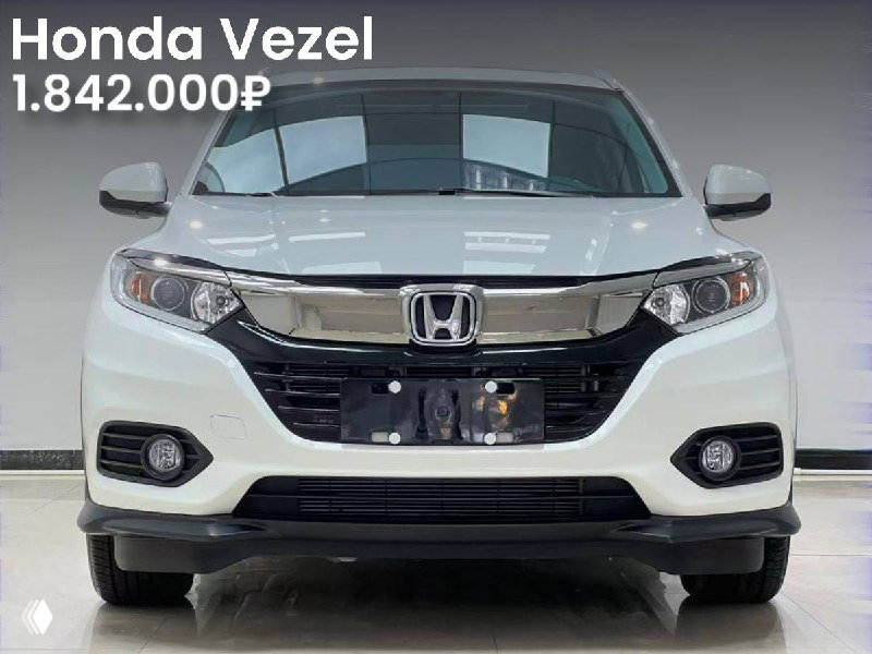 Фронтальный вид белого Honda Vezel 2021 года: отчётливые фары и декоративная накладка на решётке, на фото отображена цена 1.842.000₽, автомобиль в салоне.