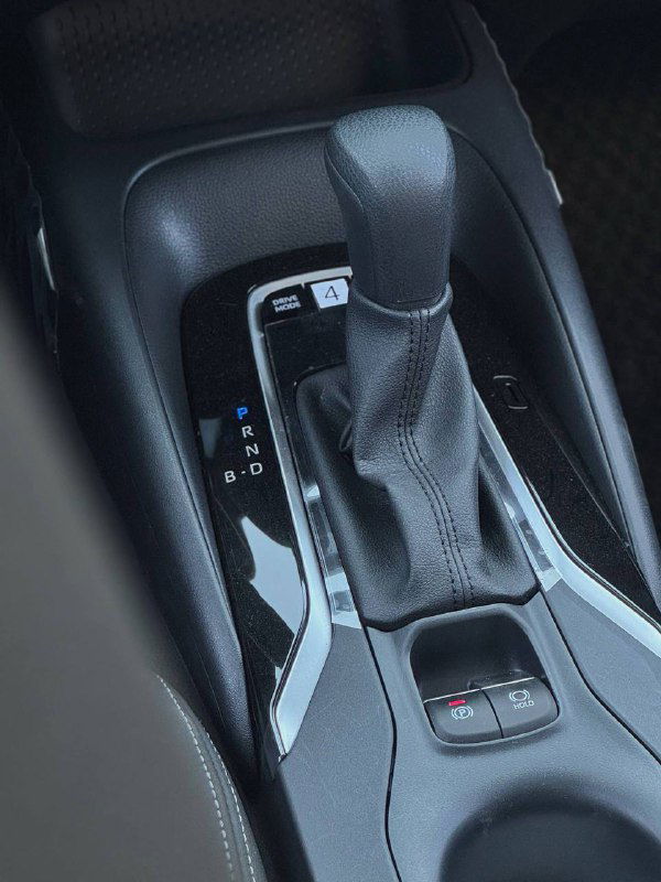 Рычаг переключения передач и центральный тоннель Toyota Corolla 2022, крупный план селектора АКПП и кнопок рядом с ним.