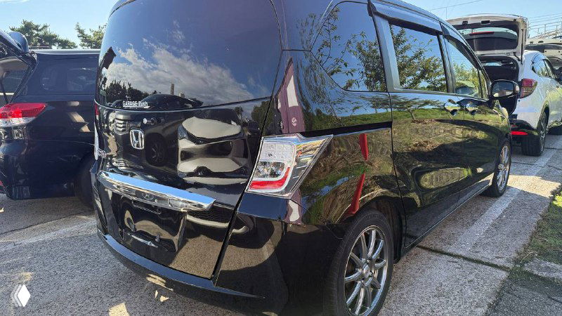 Чёрный Honda Freed 2012, вид сзади и боковой стороны на стоянке; показывает форму кормы, задние фонари и общий внешний вид для объявлений импорта.