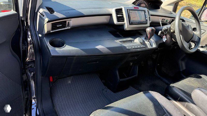 Салон Honda Freed 2012: приборная панель, центральная консоль и передние сиденья — фото интерьера автомобиля, демонстрирующее состояние обивки и торпеды.