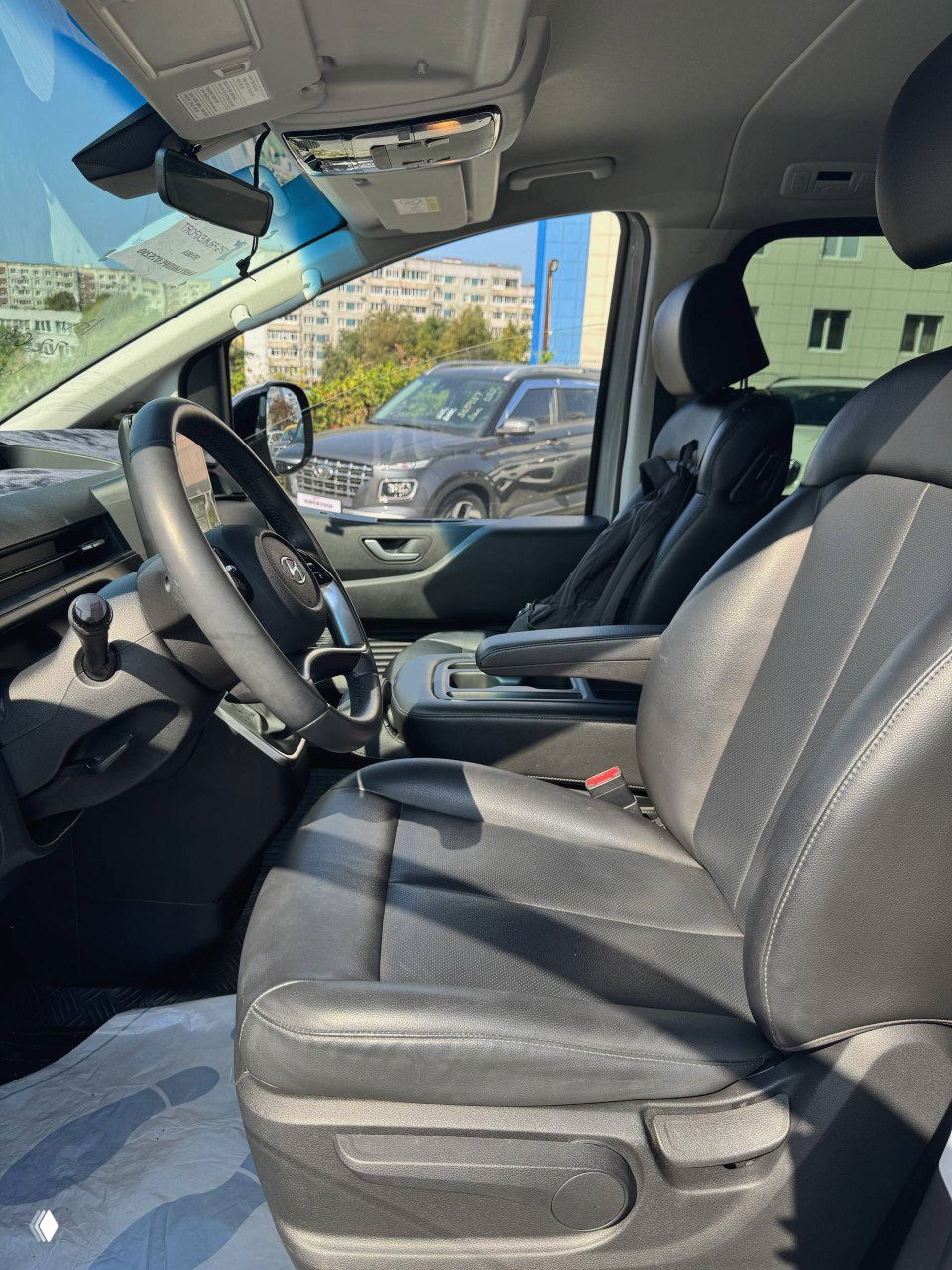 Переднее сиденье водителя в кожаной отделке, вид на рулевую колонку и часть центрального подлокотника, салон выглядят ухоженными