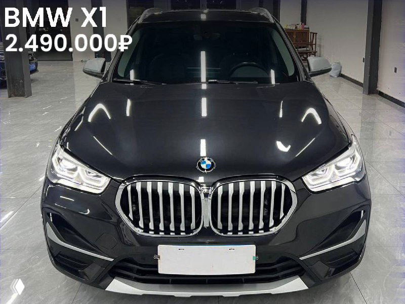 Темный BMW X1 sDrive 20Li 2022 года, фронтальный вид в крытом боксе; на изображении указана цена 2.490.000 ₽ и отметка «Без окрасов».