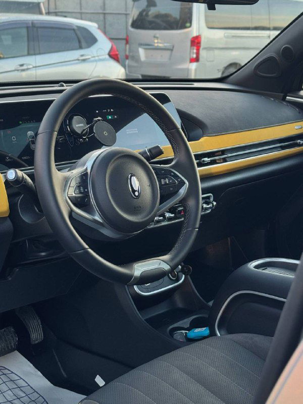 Передняя панель и руль Ora 03 GT: мультируль, экран приборов, вентиляционные решётки и интерьер с контрастными жёлтыми вставками, вид из водительской зоны.