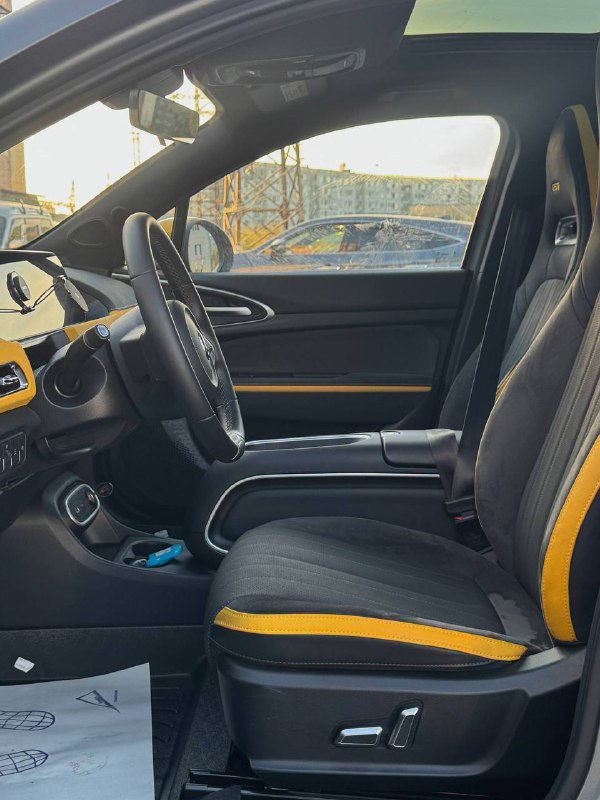 Вид на переднее пассажирское сиденье и центральный тоннель Ora 03 GT: комфортные подлокотники, отделка сидений и жёлтые декоративные элементы в интерьере.