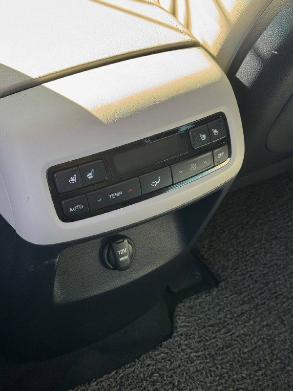 Крупный план блока управления климатом и розетки в задней части центральной консоли Hyundai Palisade, видно кнопки подогрева и регуляторы климата.