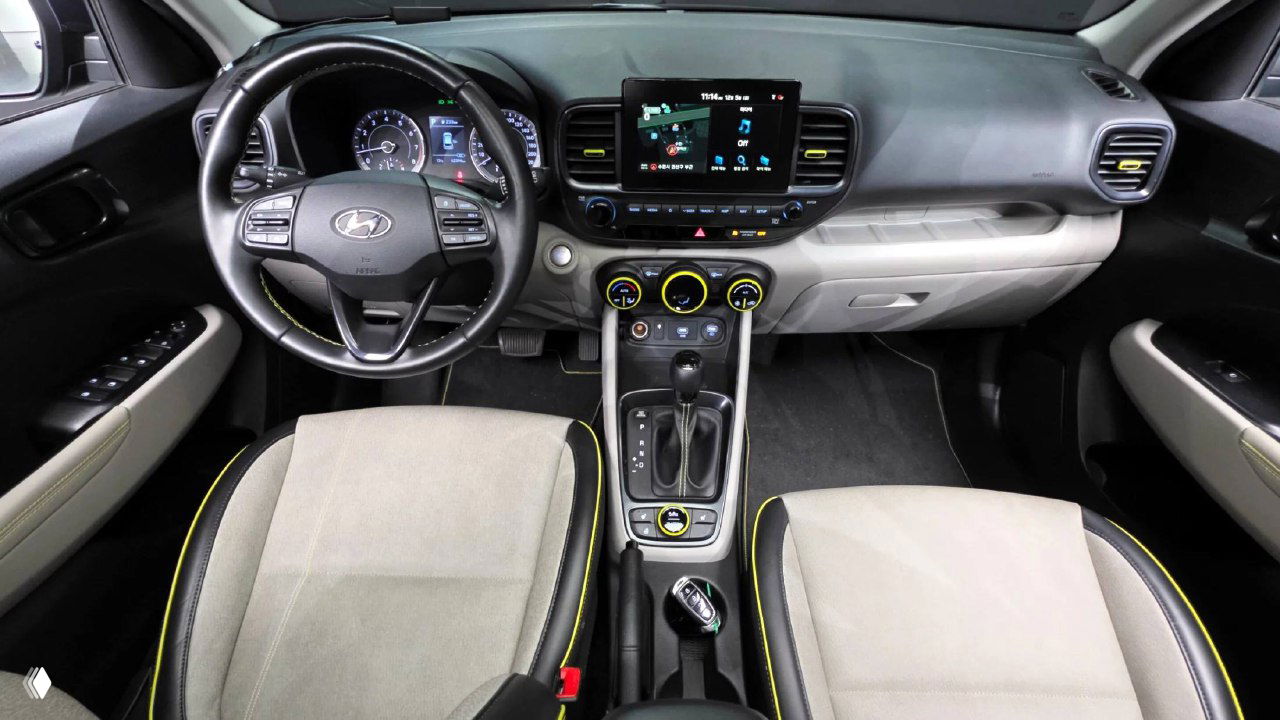 Салон Hyundai Venue: руль с мультирулем, приборная панель, крупный экран мультимедиа и светлая тканевая обивка сидений с жёлтой прострочкой.