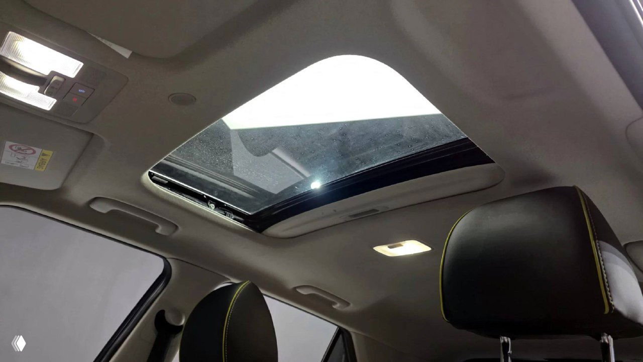 Панорамный люк Hyundai Venue: открытый люк в крыше, вид сзади на потолок салона и передние подголовники с контрастной прострочкой.