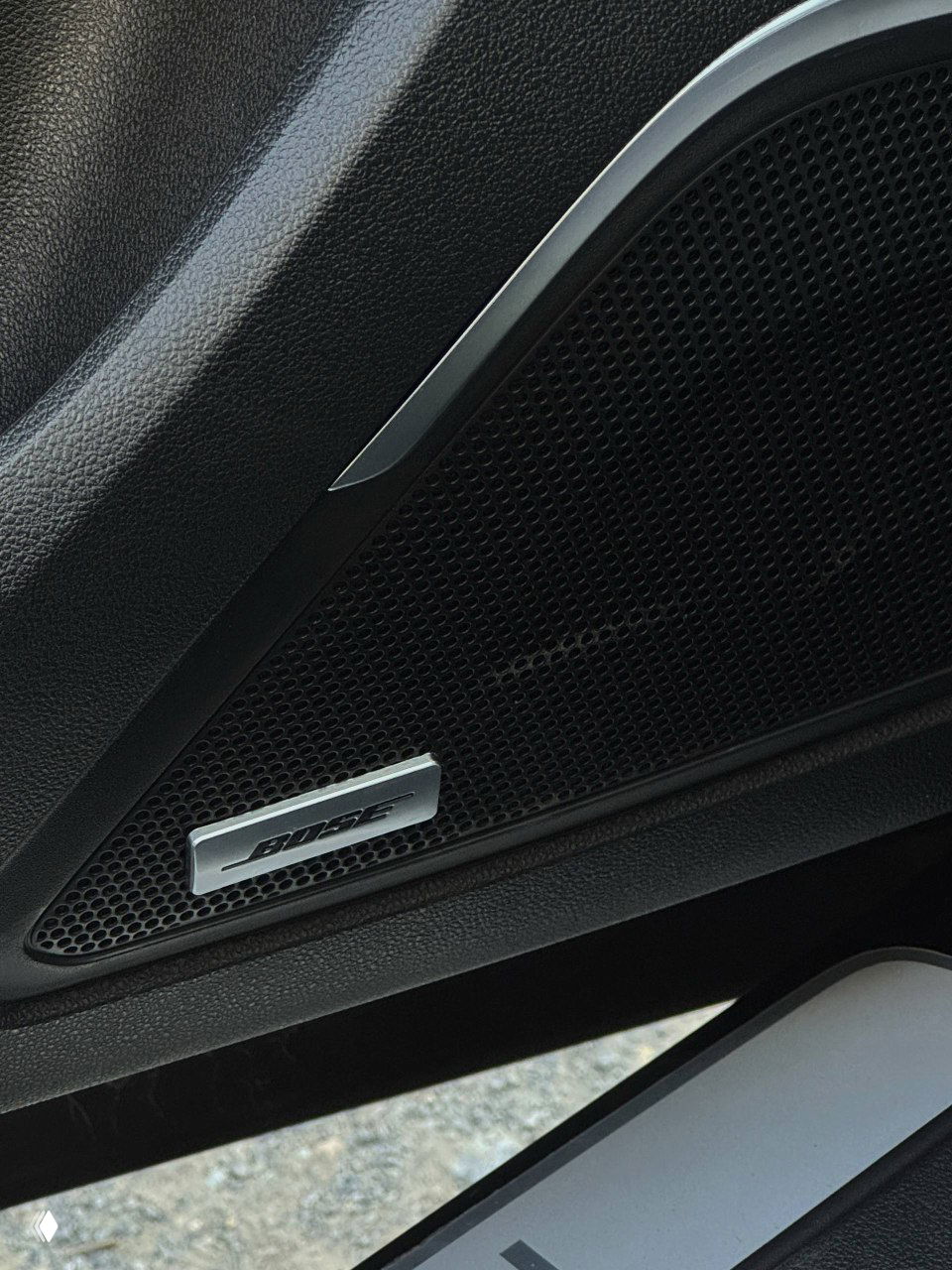 Крупный план динамика Bose в дверной панели Samsung QM6, видна эмблема Bose и текстура отделки, фото для иллюстрации комплектации аудиосистемы