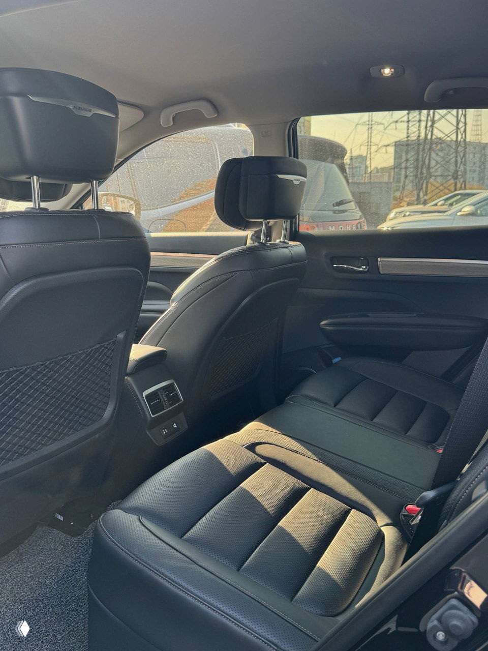 Вид на задние сиденья Samsung QM6: чёрная кожаная обивка, подголовники, пространство для ног и вид задней части центральной консоли