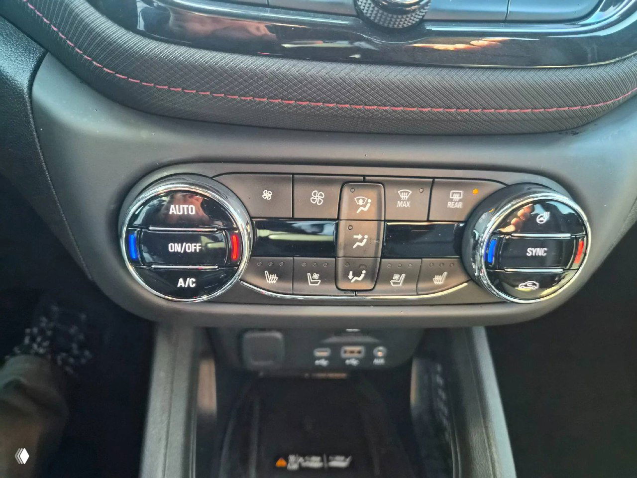 Панель управления климатом и сиденья: крупный план контроллеров климата, кнопок подогрева и отделки с декоративной прострочкой в передней части салона.