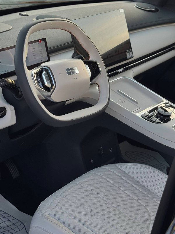 Общий вид передней части салона Geely Galaxy Starship 7: белые сиденья, рулевая колонка и большая центральная консоль, интерьер снят под углом