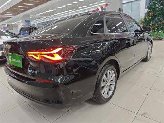 Задняя правая часть чёрного Chevrolet Monza: яркие задние фонари и чистый бампер; автомобиль показан в широко освещённом шоу-руме.