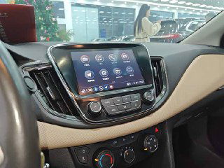 Крупный план мультимедиа-экрана и климат-контроля Chevrolet Monza; сенсорные и механические органы управления на центральной панели.